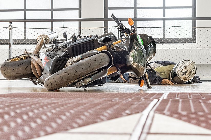 Eine Motorradfahrerpuppe liegt neben einer umgekippten Maschine
